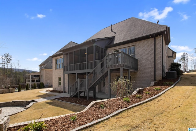 back of property with central air condition unit, brick siding, a sunroom, stairs, and a patio area