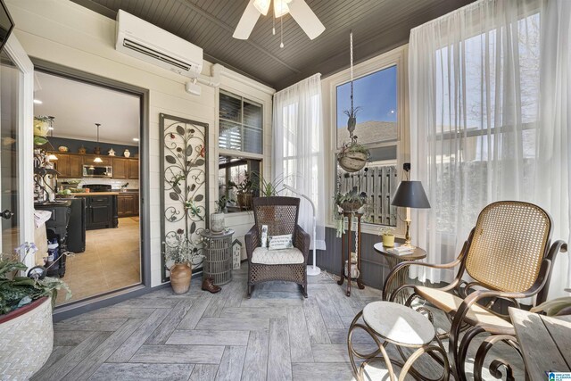 sitting room with an AC wall unit and ceiling fan