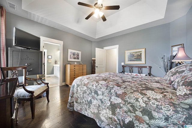 bedroom featuring visible vents, dark wood-type flooring, a ceiling fan, a tray ceiling, and baseboards