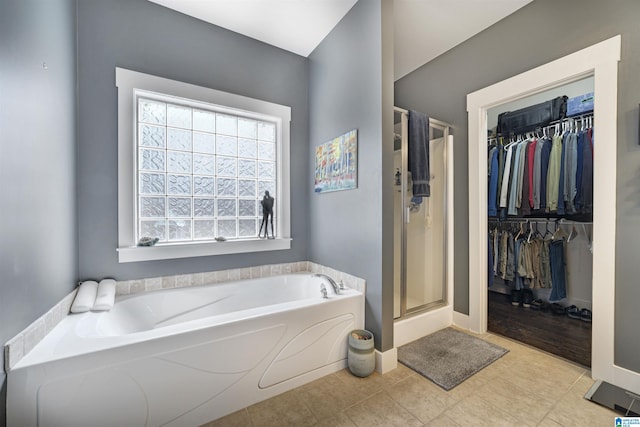 bathroom featuring baseboards, a stall shower, a spacious closet, a garden tub, and tile patterned floors