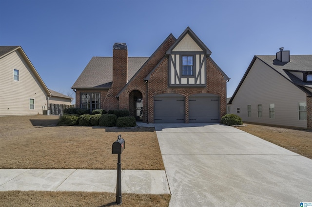 english style home with roof with shingles, concrete driveway, a garage, brick siding, and a chimney