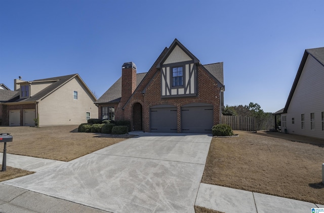 english style home with brick siding, fence, roof with shingles, a garage, and driveway