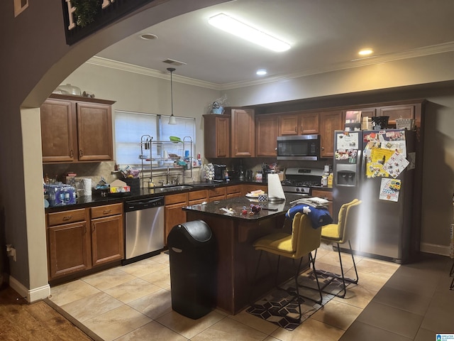 kitchen featuring a kitchen breakfast bar, appliances with stainless steel finishes, decorative backsplash, dark countertops, and crown molding