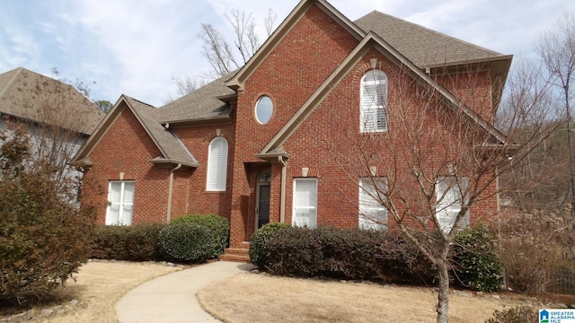 traditional-style house with roof with shingles and brick siding