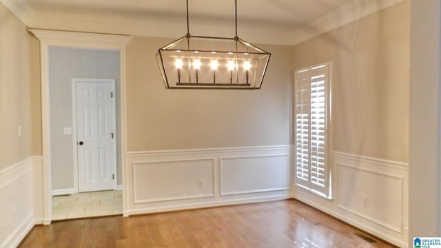 unfurnished dining area with a wealth of natural light, wood finished floors, visible vents, and crown molding