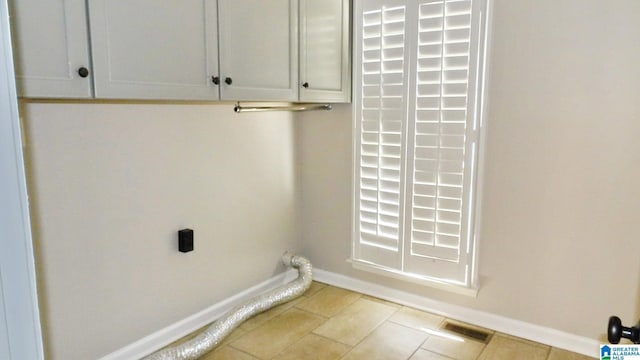 clothes washing area with cabinet space, visible vents, baseboards, tile patterned flooring, and electric dryer hookup