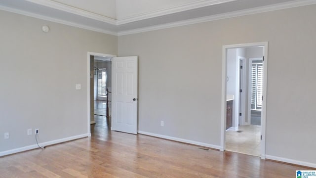 empty room featuring visible vents, ornamental molding, a wealth of natural light, and wood finished floors