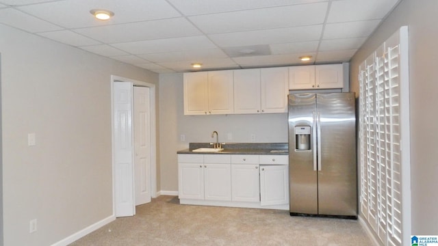 kitchen featuring light colored carpet, a sink, white cabinetry, stainless steel fridge with ice dispenser, and dark countertops