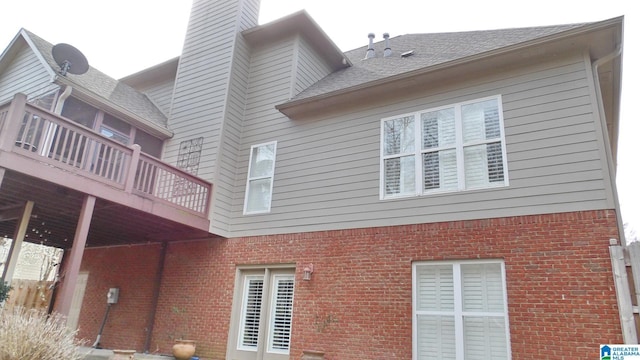 view of home's exterior featuring roof with shingles, a chimney, and brick siding