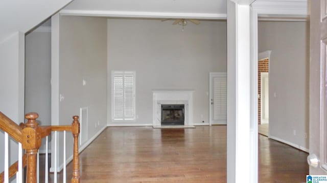 unfurnished living room featuring a fireplace with raised hearth, wood finished floors, and baseboards