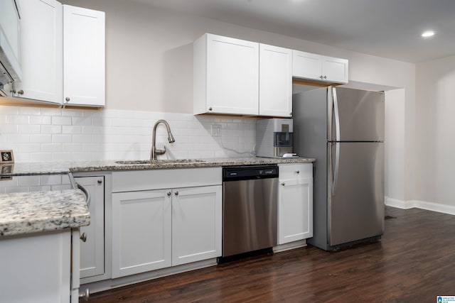 kitchen with tasteful backsplash, appliances with stainless steel finishes, dark wood-type flooring, white cabinetry, and a sink