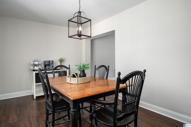 dining room with a notable chandelier, dark wood finished floors, and baseboards