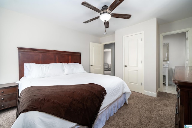 carpeted bedroom with ceiling fan, ensuite bath, and baseboards