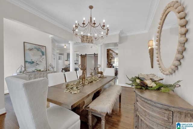 dining space with a barn door, wood finished floors, baseboards, decorative columns, and crown molding