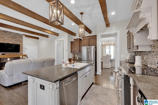 kitchen featuring tasteful backsplash, dark stone counters, appliances with stainless steel finishes, open floor plan, and beamed ceiling