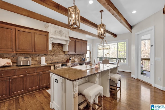 kitchen with stainless steel range, dark wood finished floors, a breakfast bar, a sink, and backsplash