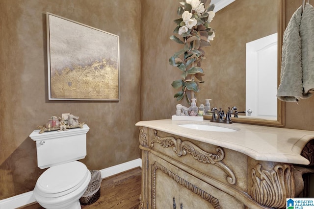 half bathroom featuring baseboards, vanity, toilet, and wood finished floors