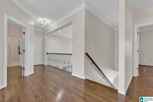 hall featuring baseboards, wood finished floors, an upstairs landing, and crown molding