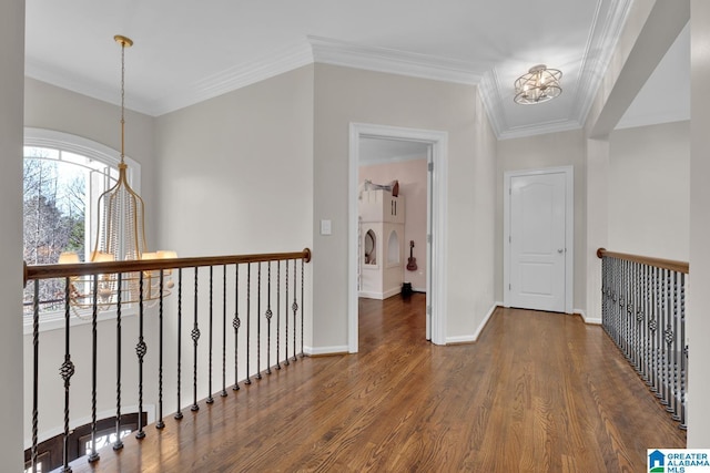 hall featuring baseboards, ornamental molding, wood finished floors, and a notable chandelier