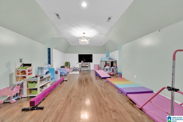 game room featuring lofted ceiling, a notable chandelier, visible vents, and wood finished floors