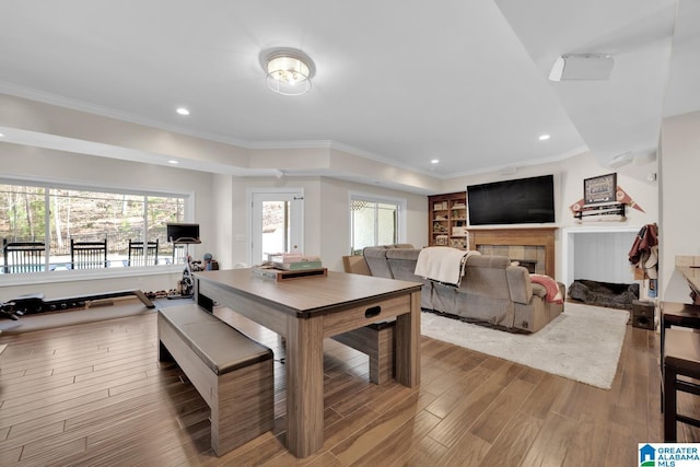 dining room with ornamental molding, recessed lighting, a tiled fireplace, and wood finished floors