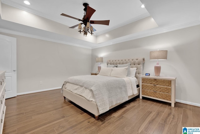 bedroom featuring a raised ceiling, baseboards, and wood finished floors