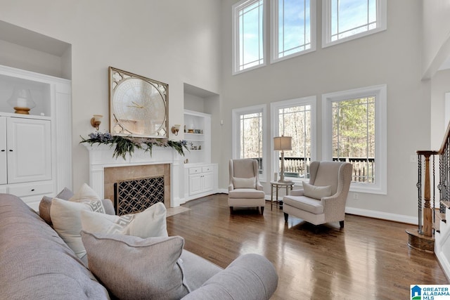 living room featuring a wealth of natural light, dark wood finished floors, a fireplace, and stairs