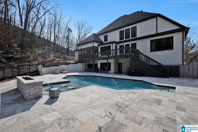 view of pool with stairway, a patio area, a deck, a fenced backyard, and a fire pit