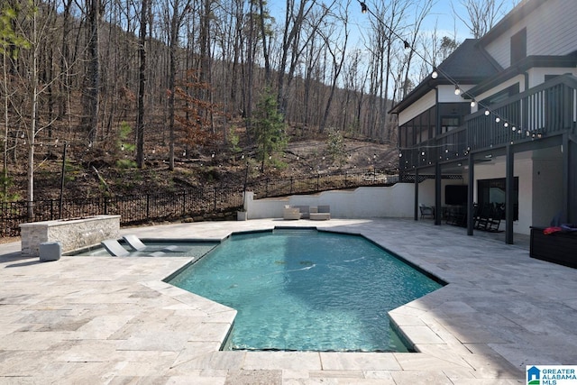 view of pool with a patio, a forest view, fence, and a fenced in pool