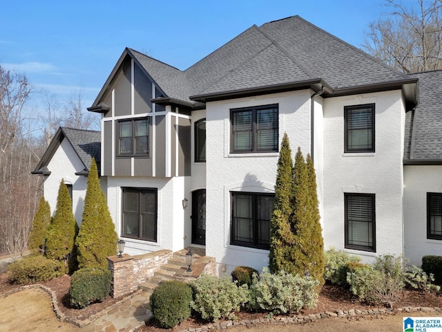 view of front of property with a shingled roof and brick siding