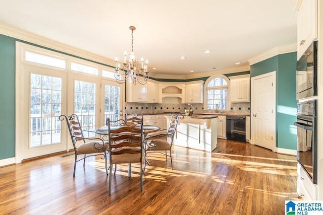 dining space featuring baseboards, ornamental molding, wood finished floors, and a notable chandelier