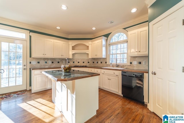 kitchen featuring dark countertops, stainless steel gas stovetop, ornamental molding, a sink, and dishwasher