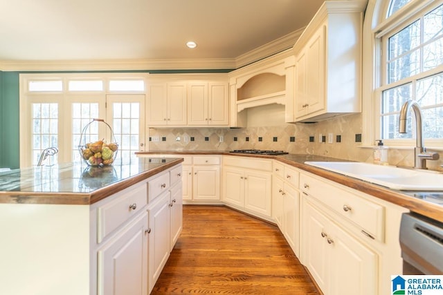 kitchen featuring stainless steel gas stovetop, light wood-style flooring, decorative backsplash, a sink, and dishwasher