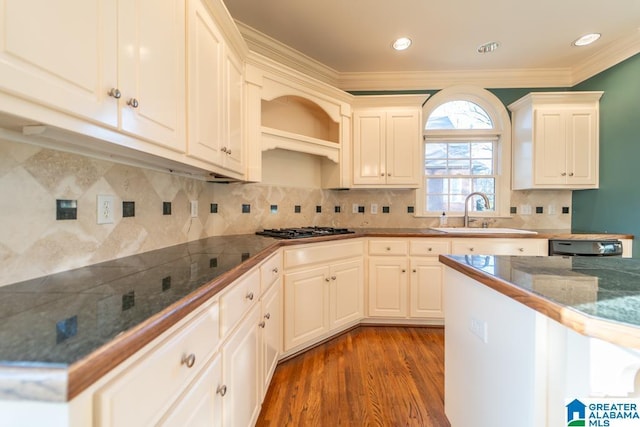 kitchen with ornamental molding, wood finished floors, a sink, gas cooktop, and backsplash