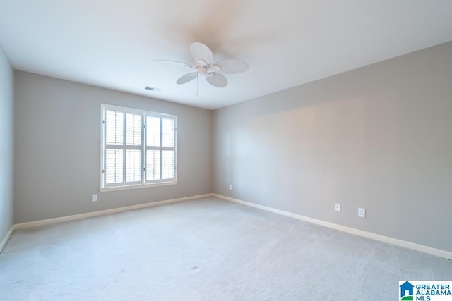 carpeted spare room featuring ceiling fan, visible vents, and baseboards