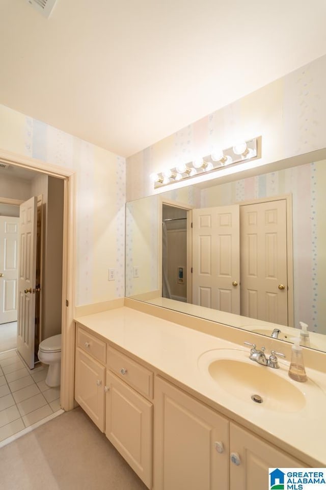 bathroom with toilet, wallpapered walls, tile patterned flooring, and vanity