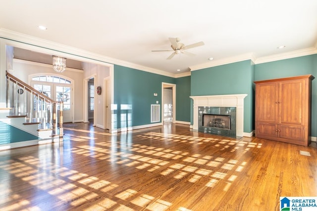 unfurnished living room featuring stairs, baseboards, a premium fireplace, and wood finished floors