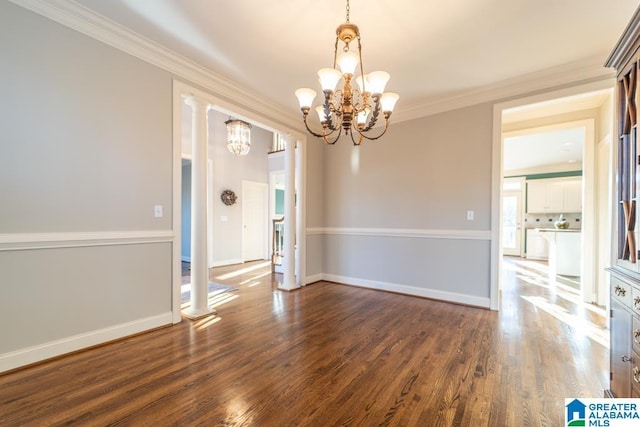 unfurnished dining area featuring a chandelier, wood finished floors, baseboards, decorative columns, and crown molding