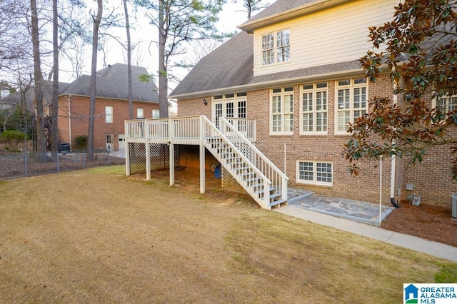 rear view of property featuring stairway, fence, a deck, a yard, and brick siding