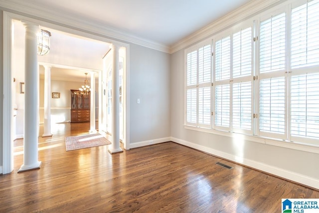 empty room featuring ornate columns, visible vents, crown molding, and wood finished floors