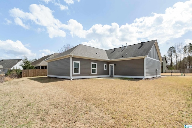 back of property featuring a lawn and fence