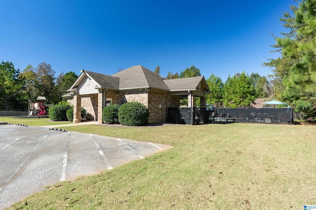 view of property exterior with brick siding, a lawn, a playground, and fence