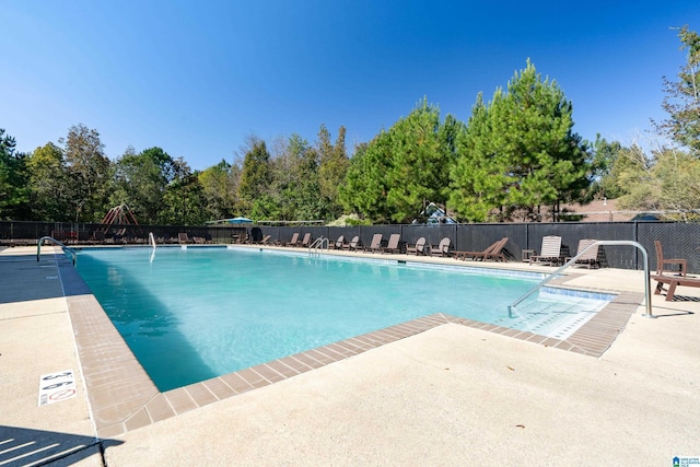 community pool with a patio area and fence