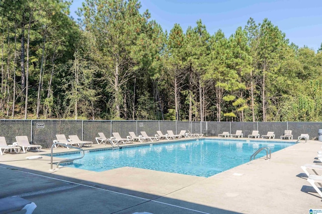 pool with a patio area and fence