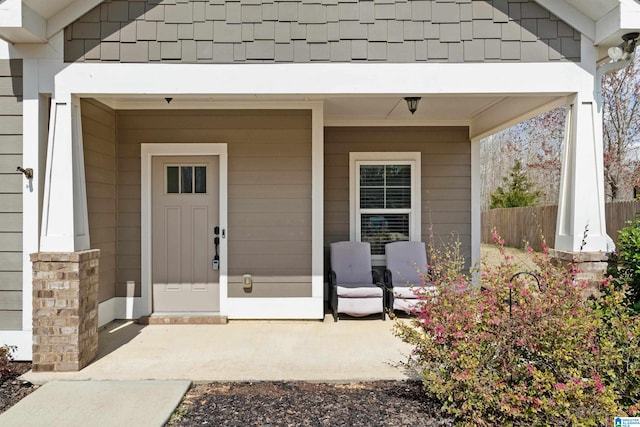 entrance to property featuring a porch and fence