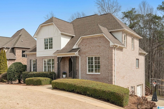 view of front of house featuring a garage, concrete driveway, brick siding, and roof with shingles