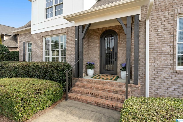 property entrance featuring brick siding and a shingled roof