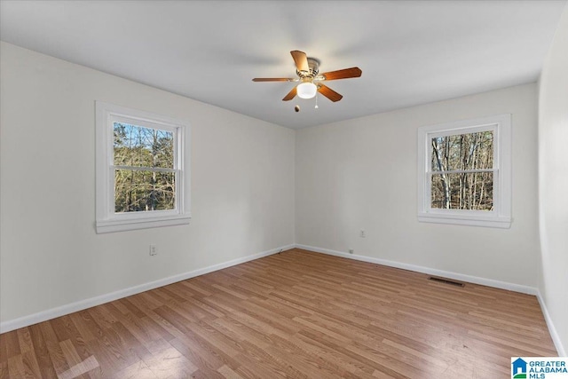 unfurnished room featuring light wood-type flooring, baseboards, visible vents, and a wealth of natural light