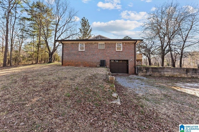 view of side of home featuring an attached garage, driveway, and brick siding