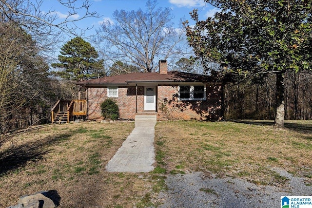 view of front of property featuring a front lawn, a chimney, and brick siding